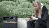 a woman sits next to a trash can that says litter recycling