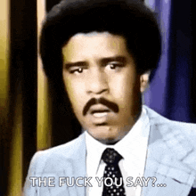 a man in a suit and tie is making a funny face and saying `` the fuck you say '' .
