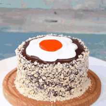 a chocolate cake with a fried egg on top is on a wooden cutting board