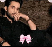 a man with a beard is sitting on a couch with a pink bow in front of him