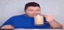 a man is sitting at a table drinking from a glass .