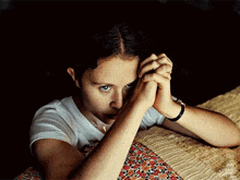 a young girl with her hands folded covering her face