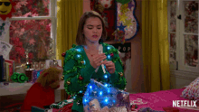 a girl in a green sweater is holding a bag of christmas lights in front of a netflix logo