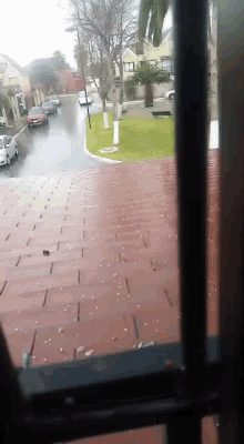 a view of a street through a window with cars parked on the side of the road
