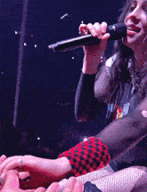a woman singing into a microphone while holding a man 's hands