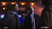 three men are standing in front of a bar with a nbc logo on the bottom