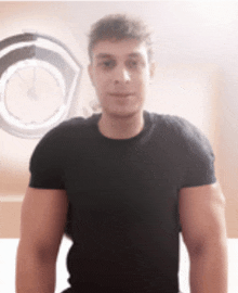 a young man in a black shirt stands in front of a clock