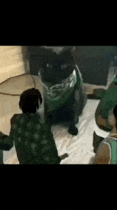 a black cat wearing a green bandana is surrounded by a group of people