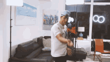 a man in a white shirt is dancing in a living room with a painting on the wall