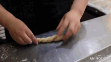 a person is twisting a piece of dough on a cutting board with the words made in animatica on the bottom