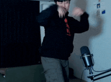 a man in a black hoodie is dancing in front of a microphone ..
