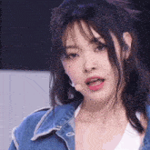 a close up of a woman wearing a denim jacket and a microphone