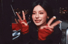 a woman wearing red gloves is smiling and giving a peace sign
