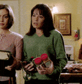 a woman in a green sweater is holding a jar with a red lid