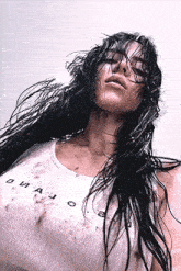 a woman with long black hair is wearing a white tank top and has a dirty shirt on .