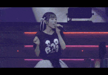 a girl is singing into a microphone while wearing a shirt with skulls on it