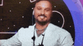 a man with a beard wearing headphones and a white shirt is smiling .