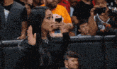 a woman taking a picture of herself in a crowd with a w logo on the bottom