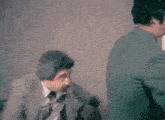 a man in a suit is touching the back of another man 's shirt