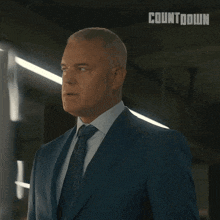 a man in a suit and tie is standing in front of a countdown sign