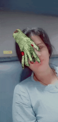 a woman covering her face with a green monster hand