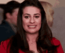 a woman in a red jacket is smiling while standing in front of a group of people .