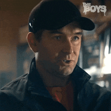 a man wearing a hat and a jacket with the word boys on the bottom