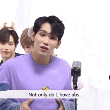 a man in a purple shirt stands in front of a microphone with the words not only do i have abs