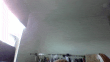 a closet with clothes hanging on a rack and a window in the background