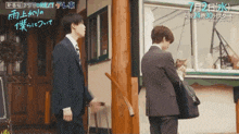 a man in a suit is holding a cat in front of a sign that says next