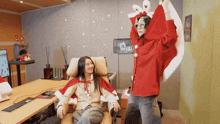 a woman in a santa cape is sitting in a chair next to another woman