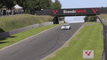 a race car is going down a track with a brand hatch sign above it