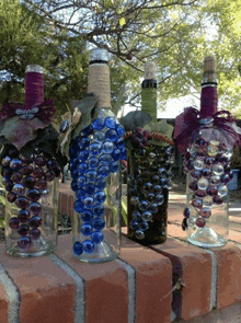 three wine bottles decorated with grapes and beads