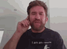 a man with a beard wearing a black shirt that says i am an