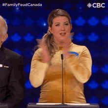 a woman stands in front of a microphone with the hashtag familyfeud canada