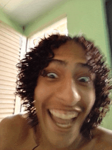a man with curly hair making a funny face with his mouth open