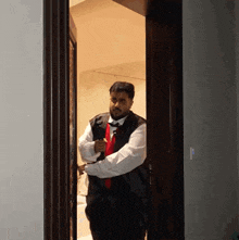 a man wearing a vest and tie is standing in a doorway