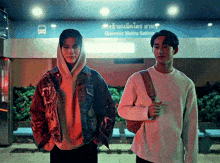 two young men standing in front of a sign that says opposite makra sathan