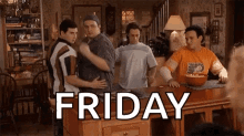 a group of men are hugging each other in a living room with the word friday written on the table .