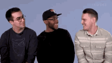 three men are sitting next to each other and one of them has an owl on his shirt .