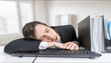 a man in a suit and tie is sleeping on a computer keyboard