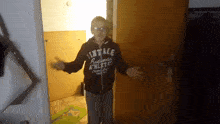 a person wearing a vintage athletics sweatshirt stands in a doorway