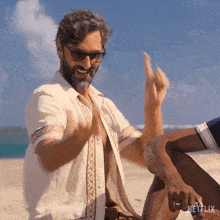 a man sitting on the beach with a netflix logo on his ring finger