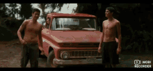 two shirtless men are standing in front of a red truck with a license plate that says 746 bc