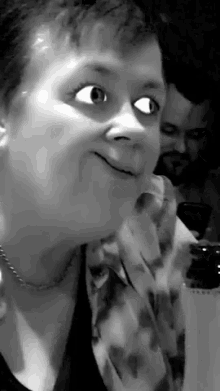 a black and white photo of a woman making a funny face with her eyes wide open .