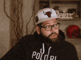 a man with a beard and glasses wearing a hat that says bulls