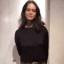 a woman wearing a black sweater is standing in front of a door .
