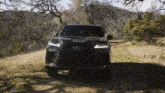 a black lexus is driving down a dirt road in the woods
