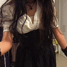 a woman with long dark hair is wearing a black dress and a white shirt