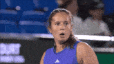 a woman wearing a purple adidas shirt looks surprised